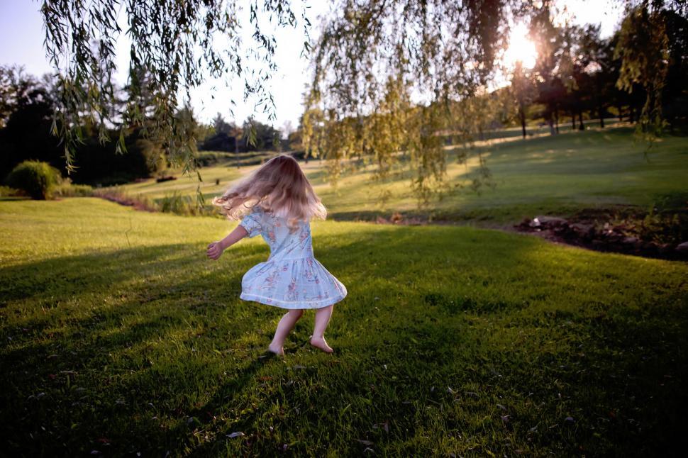 Free Image of Little girl twirling in a park at sunset 