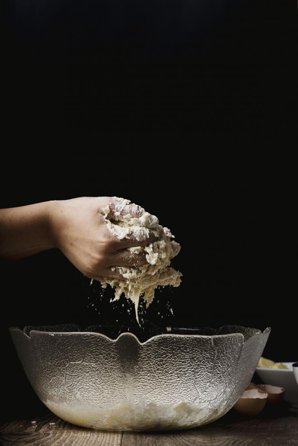 Free Image of Hand sprinkling flour in mixing bowl 