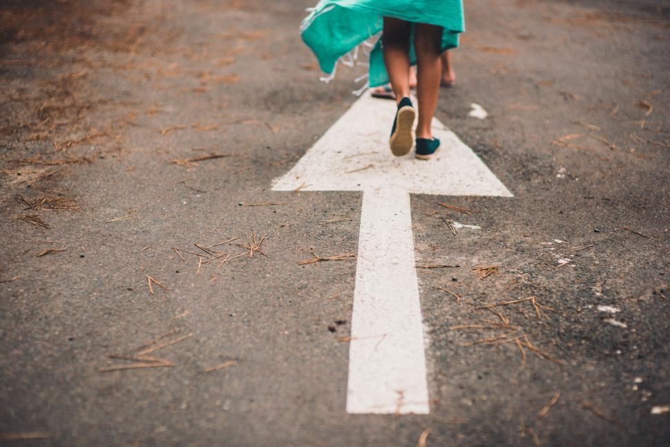 Free Image of Person walking on arrow-marked pavement 