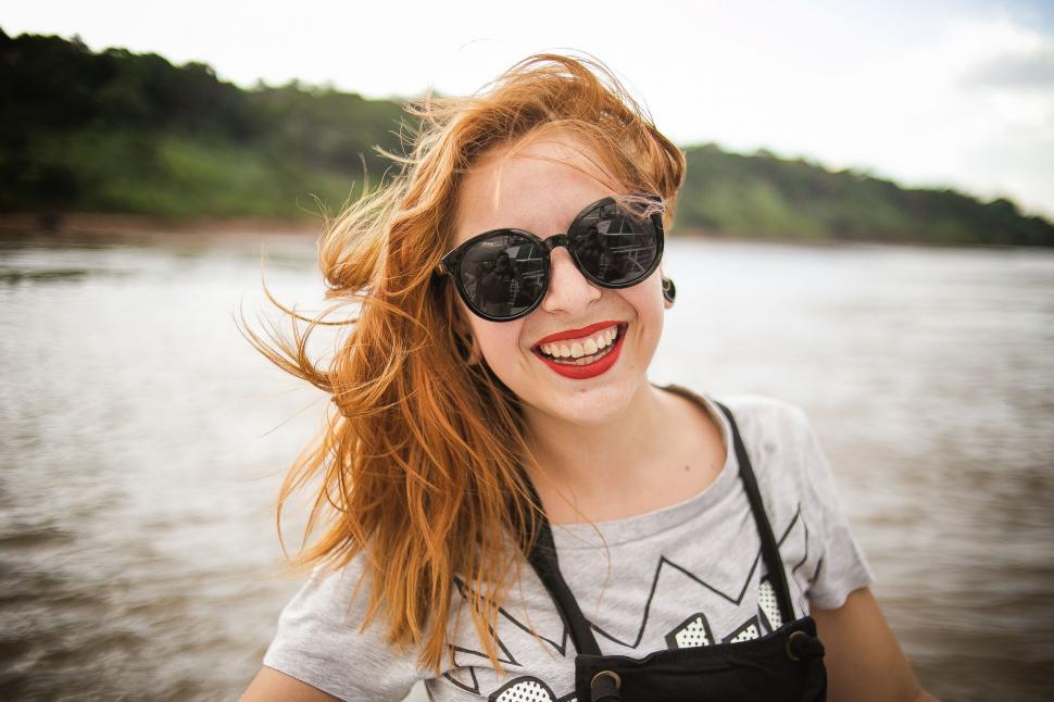 Free Image of Woman facing a river with windswept hair 