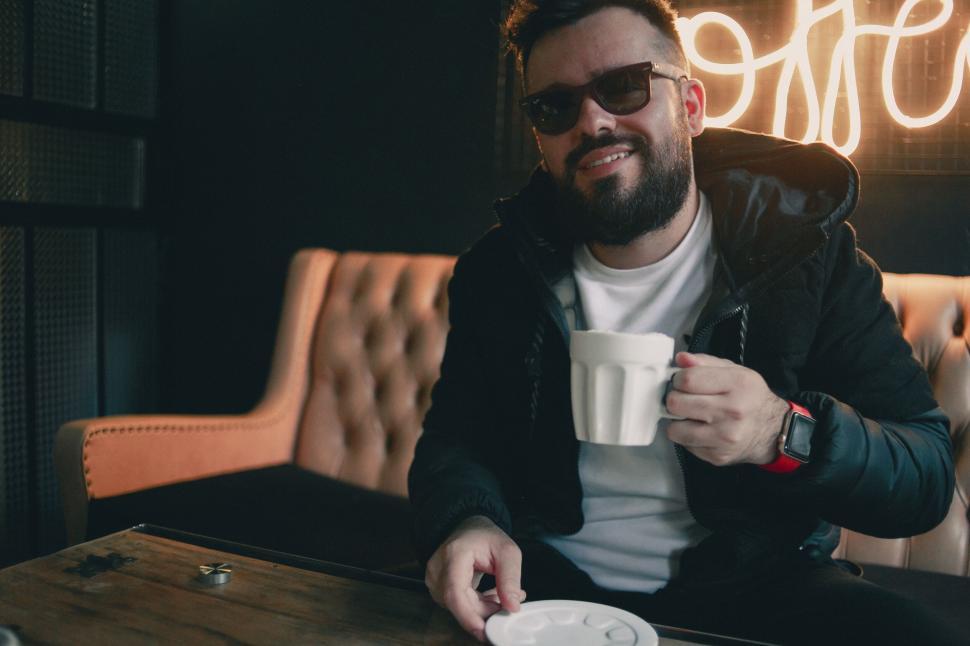 Free Image of Man with coffee cup in neon-lit cafe 