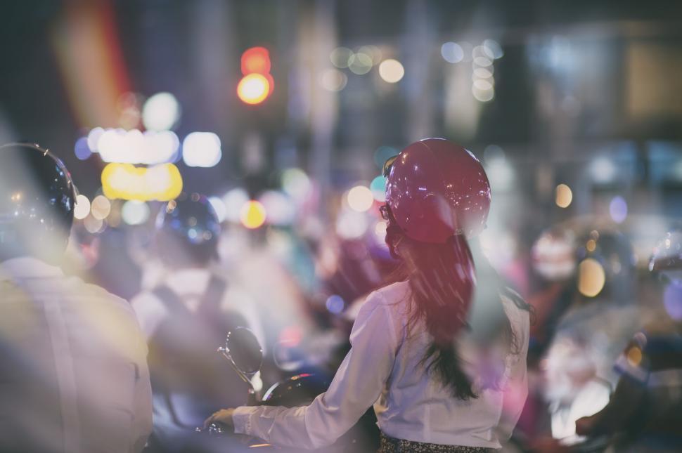Free Image of Woman on motorcycle amidst city lights 