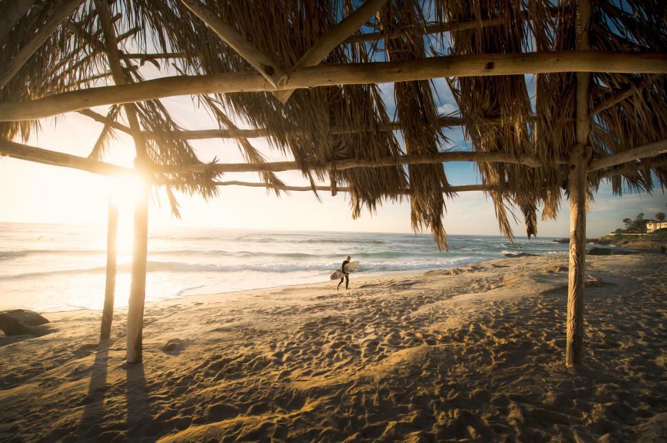 Free Image of Sunset view from a beach hut with surfer 