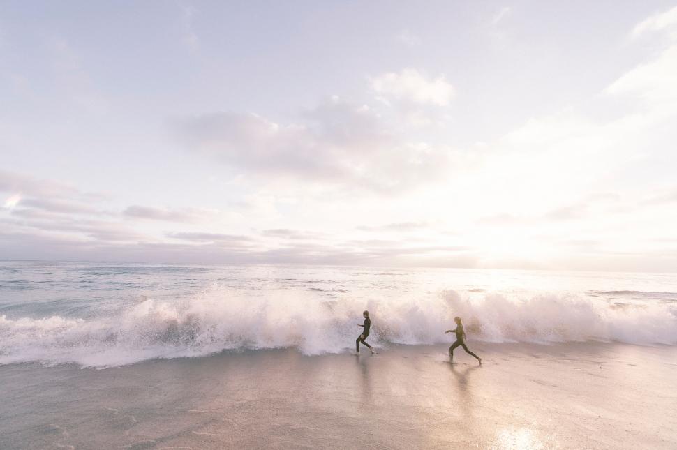 Free Image of Silhouette of two people running at surf s edge 