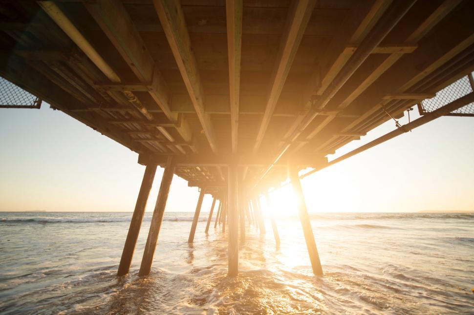 Free Image of Underneath a pier with waves during sunrise 
