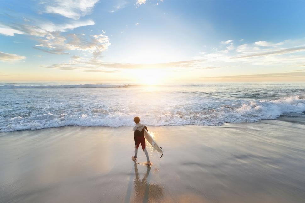 Free Image of Young surfer entering the ocean at sunrise 
