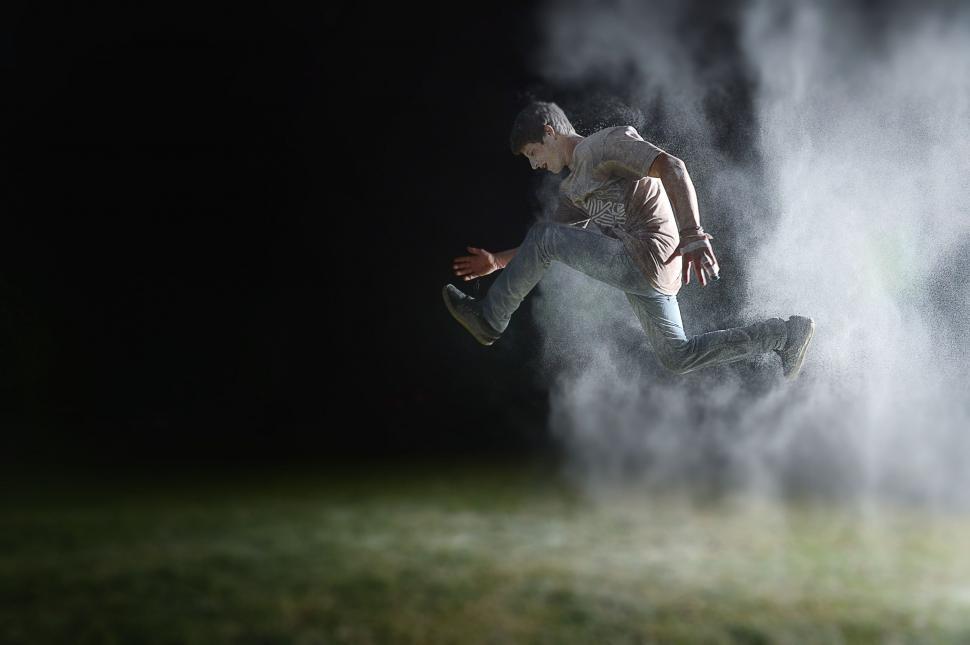 Free Image of Man jumping through foggy mist at night 