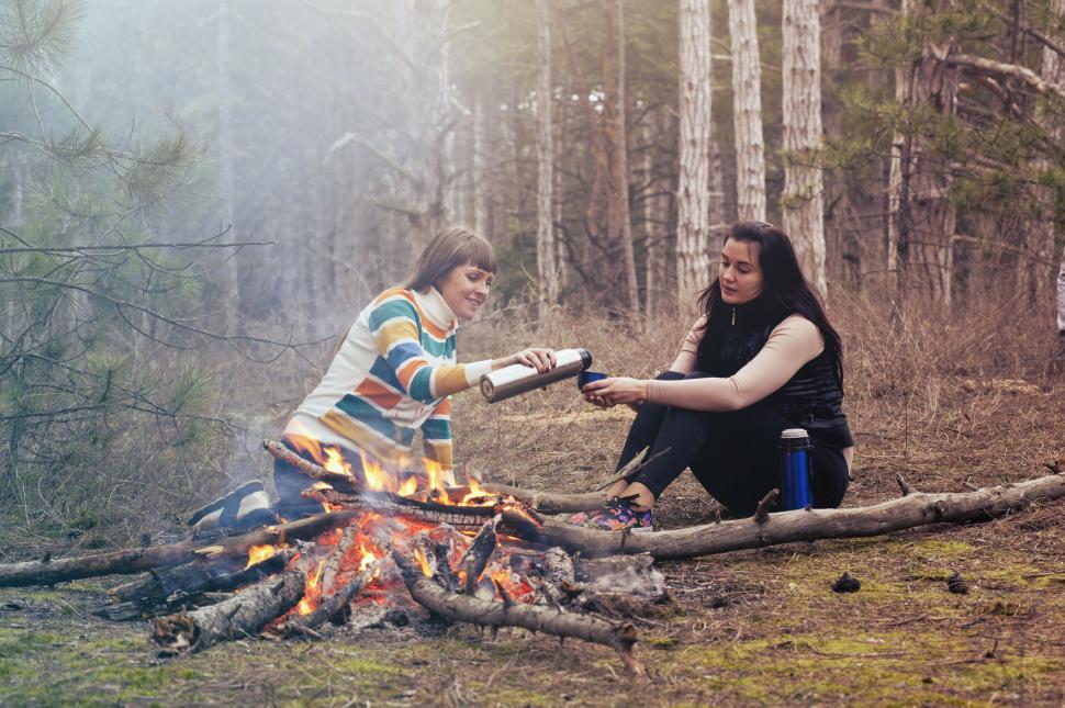Free Image of Two friends enjoying a campfire in woods 