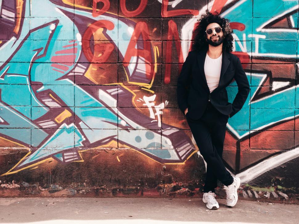 Free Image of A man leaning against a wall with graffiti 