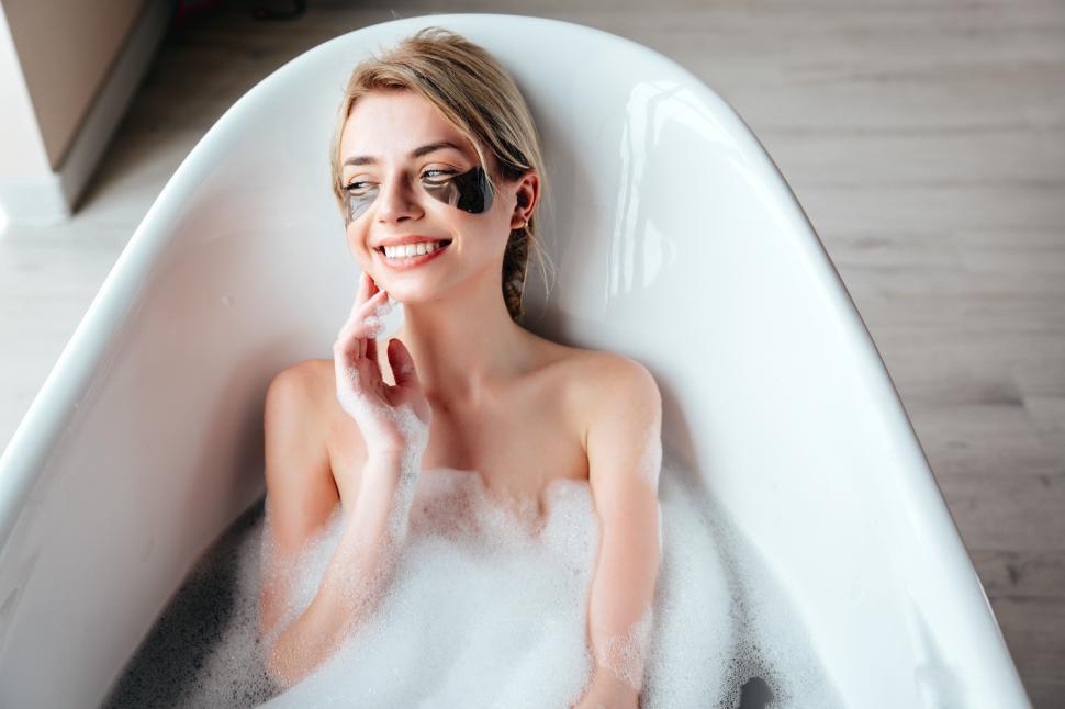Free Image of A woman lying in a bathtub with bubbles 