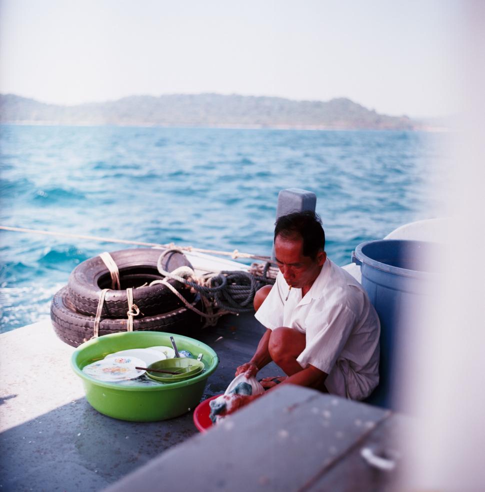 Free Image of Man washing dishes on a boat 