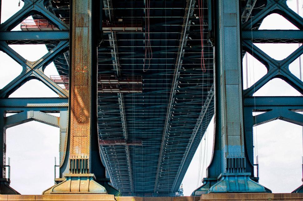 Free Image of Underbelly view of a towering blue bridge 
