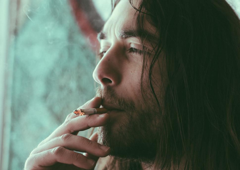 Free Image of Woman holding a cigarette with smoke 