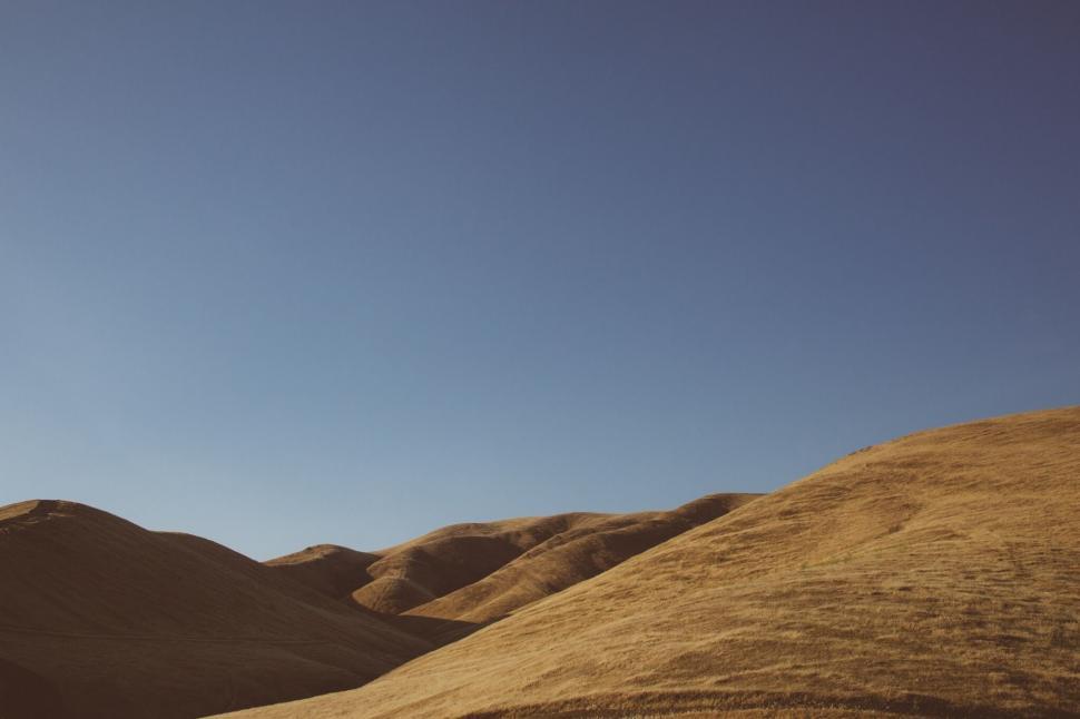 Free Image of Golden Rolling Hills Under Blue Sky 