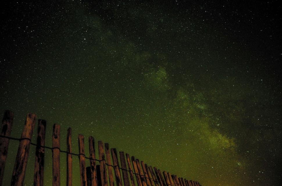 Free Image of Starry night sky over a wooden fence 
