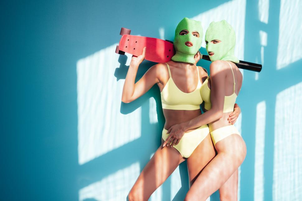 Free Image of Two women wearing ski masks and holding a skateboard 