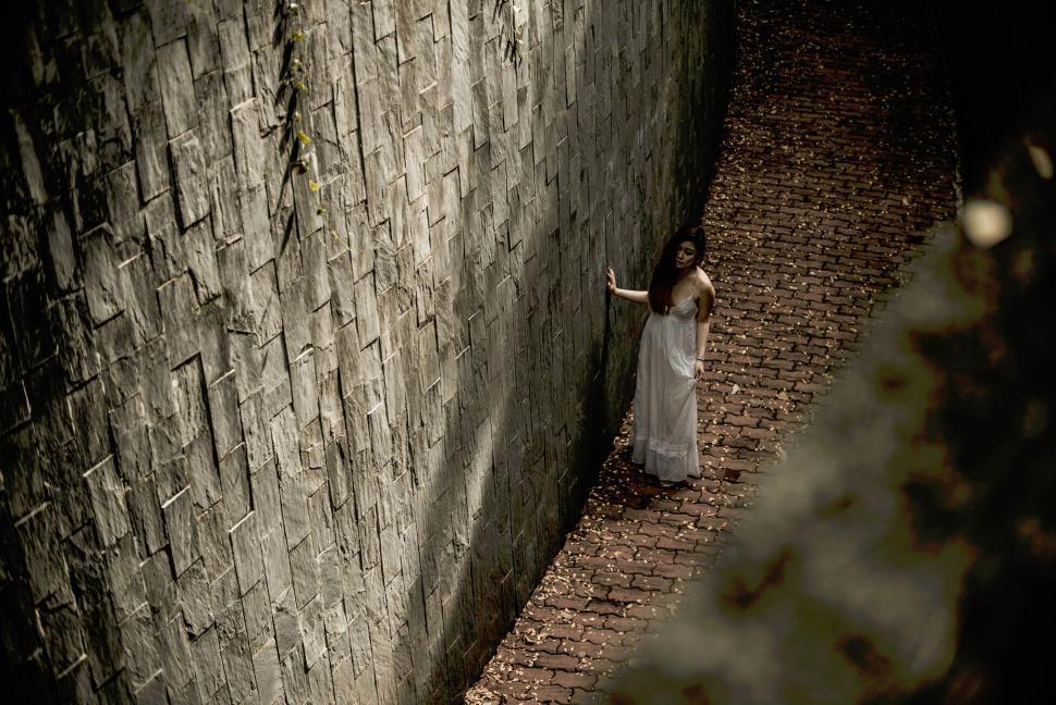 Free Image of Woman in long dress walking in narrow alley 