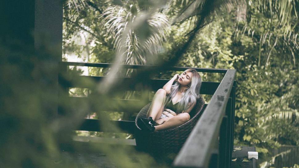 Free Image of Woman relaxing on a bench in a garden 