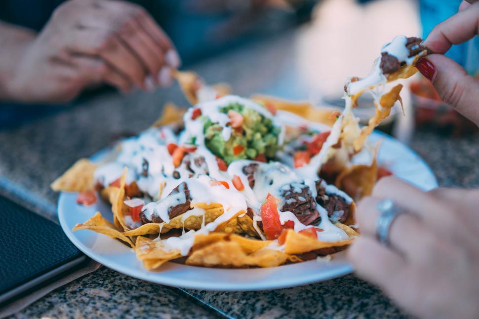 Free Image of People enjoying delicious loaded nachos 