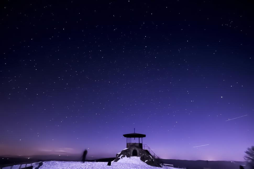 Free Image of Starry night sky above a snowy landscape with lookout 