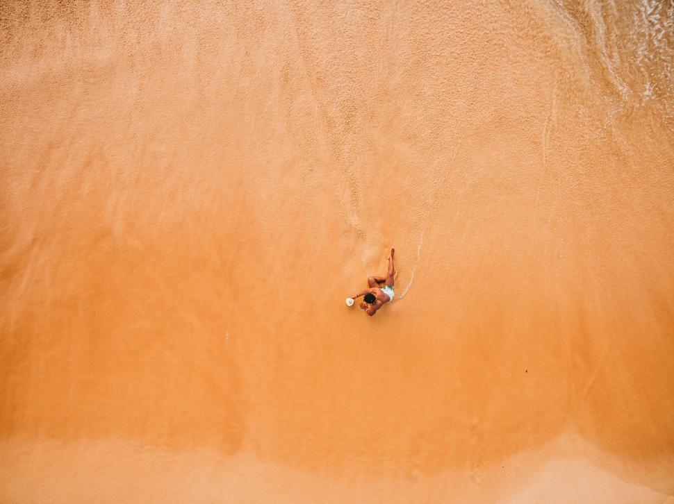 Free Image of Person lying on sandy beach from above 