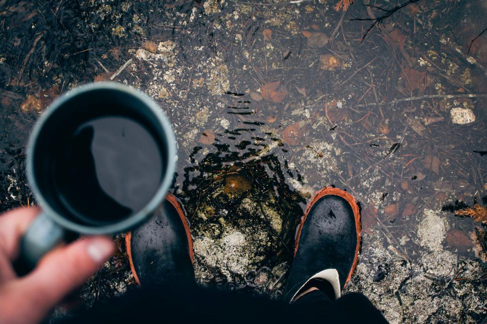 Free Image of Person holding a cup in a puddle 