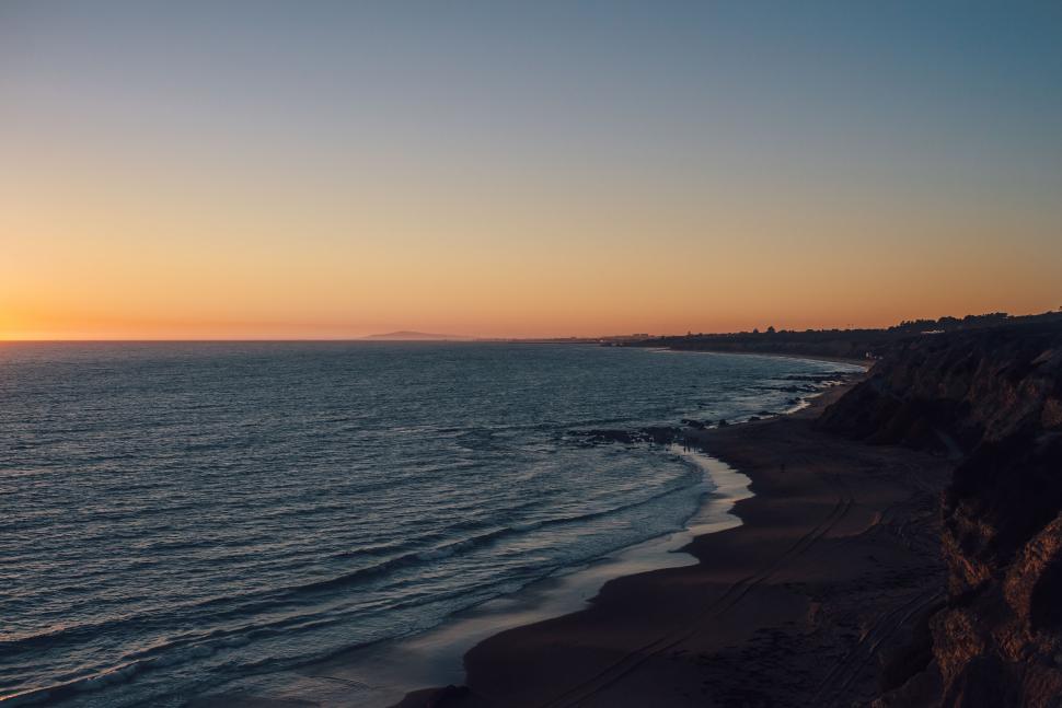 Free Image of Serene beachscape at sunset with calm sea 