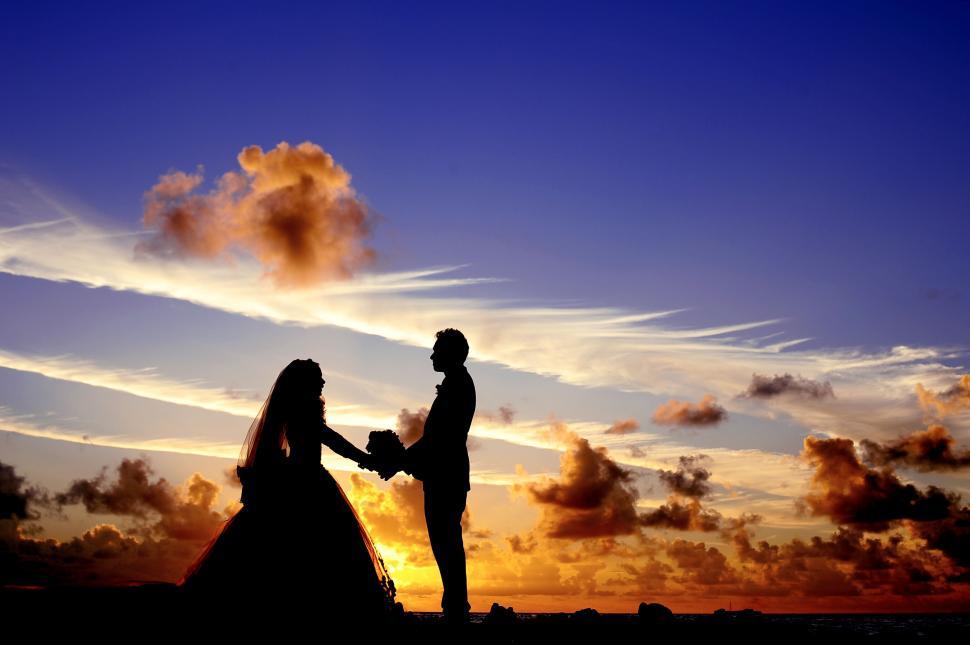 Free Image of Silhouetted couple holding hands at sunset 