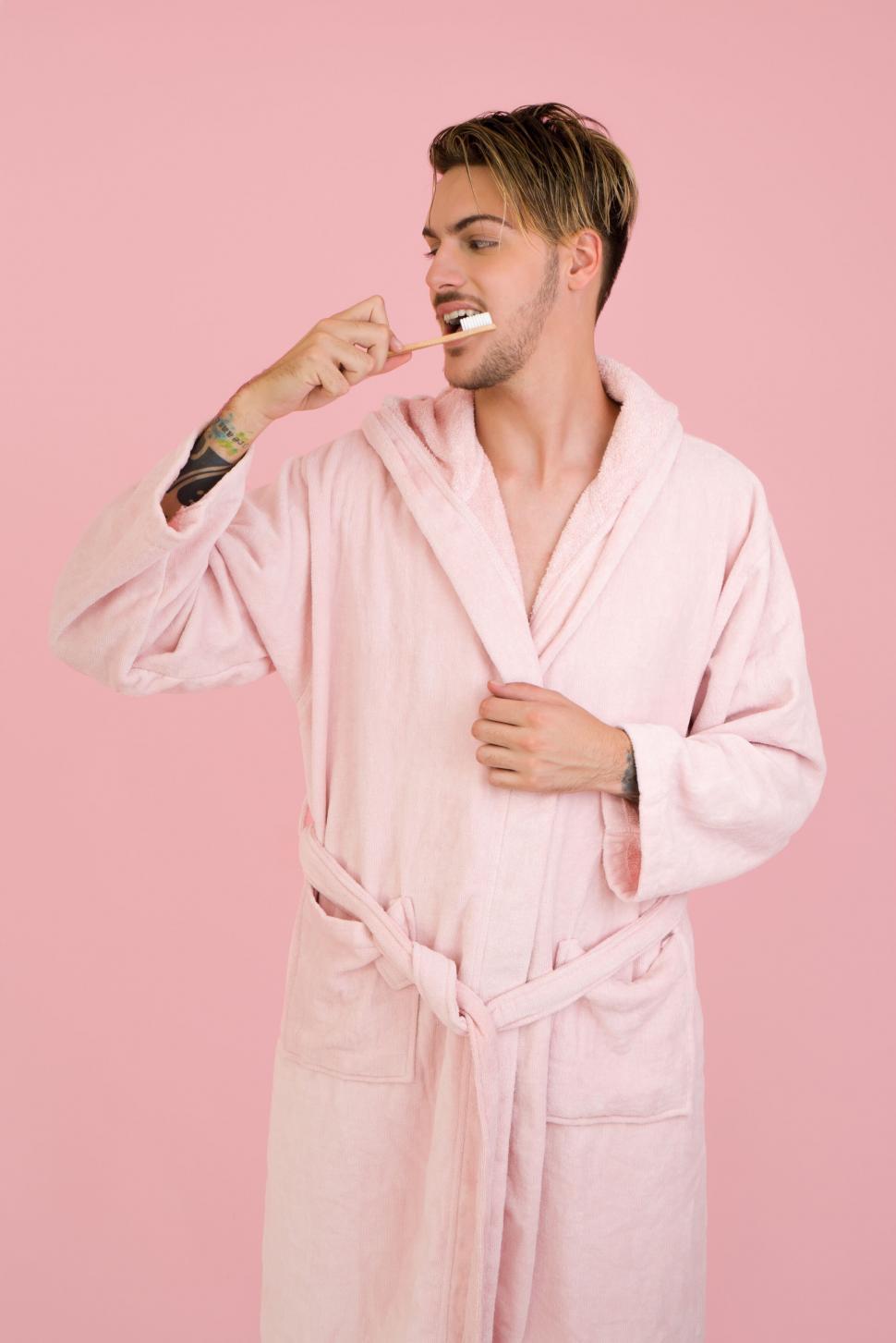 Free Image of Man in pink robe brushing teeth 