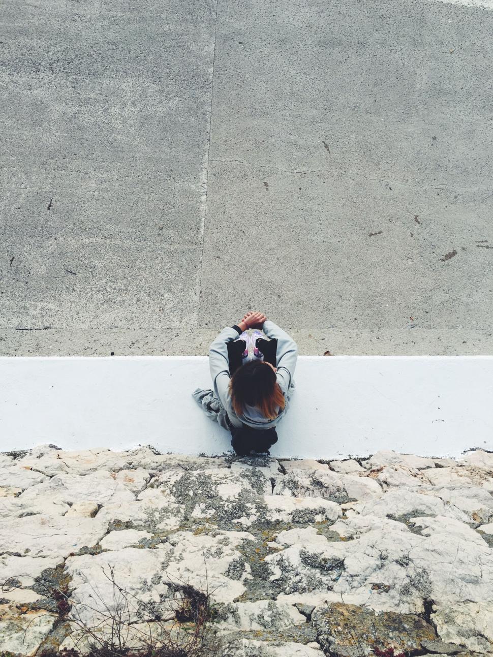 Free Image of Person sitting on edge looking down 
