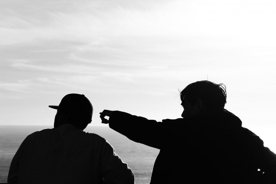 Free Image of Silhouettes of two people conversing by the sea 