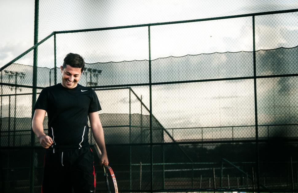 Free Image of Smiling man with tennis racket on court 