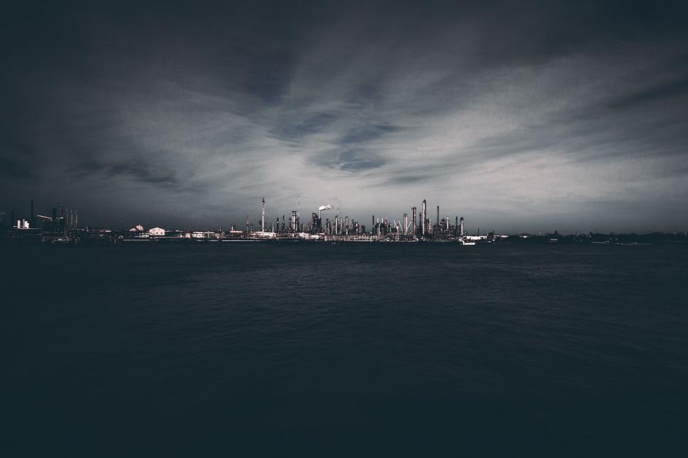Free Image of City skyline against dark, moody sky over water 