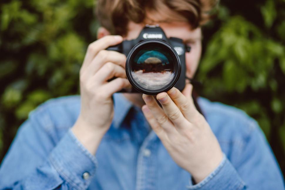 Free Image of Person holding camera covering face 