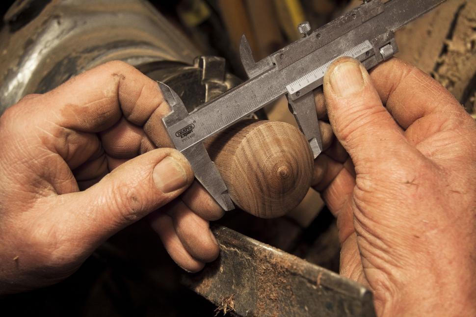 Free Image of Craftsman measuring wooden object with caliper 