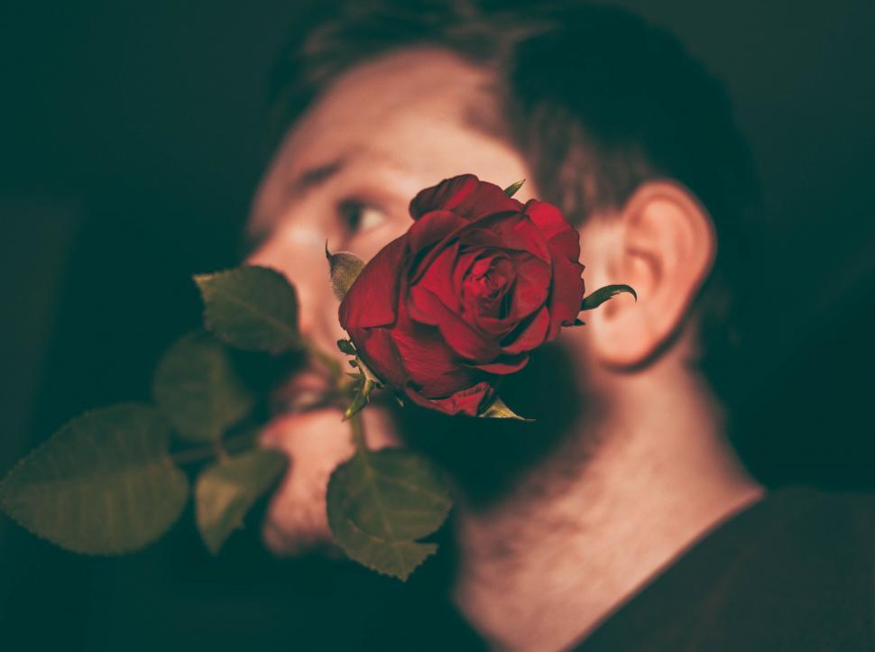 Free Image of Person with a blurred face holding roses 
