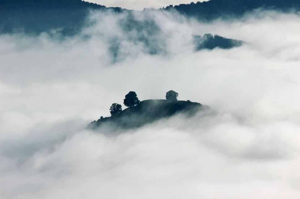 Free Image of Misty hill peeking through cloud cover 