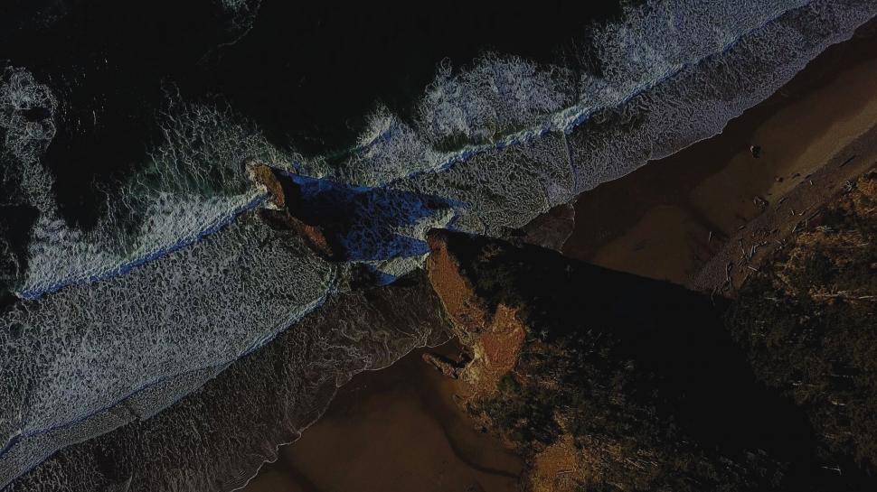 Free Image of Aerial of waves crashing on a rocky beach 