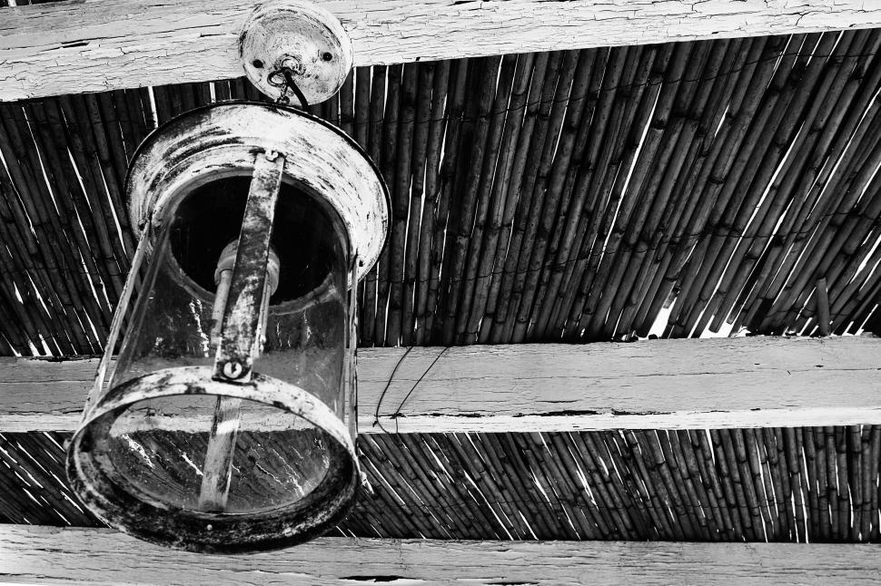 Free Image of Vintage hanging lantern against a straw roof 