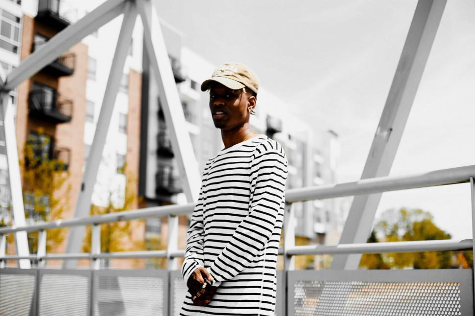 Free Image of Man in striped shirt on urban bridge 