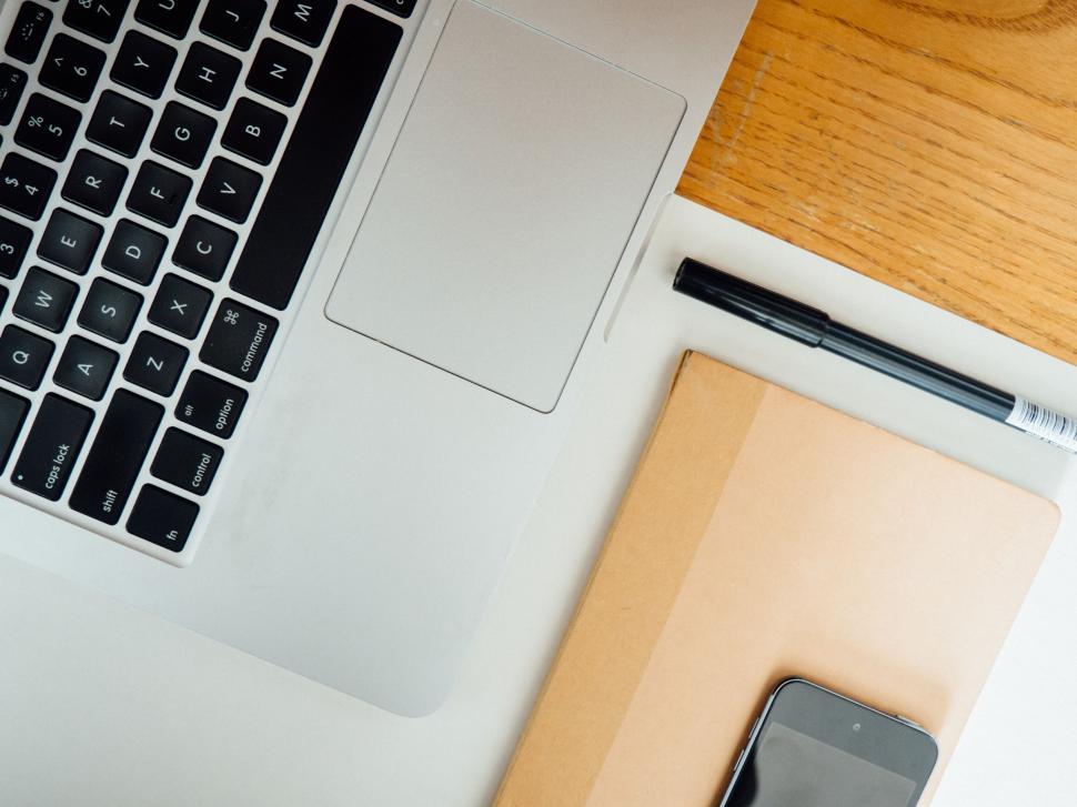 Free Image of Workspace with laptop, notebook, and phone 