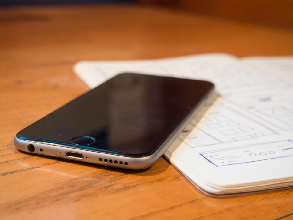 Free Image of Smartphone resting on wooden table near notebook 