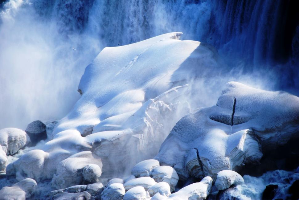 Free Image of Icy snow-covered rocks near waterfall mist 