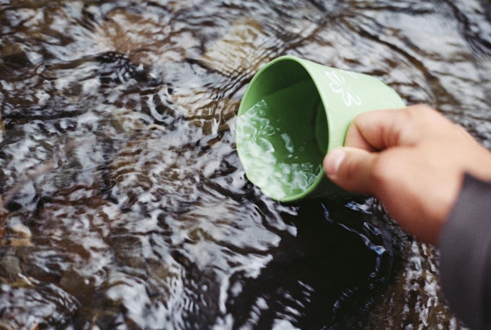 Free Image of Hand scooping water with green cup 