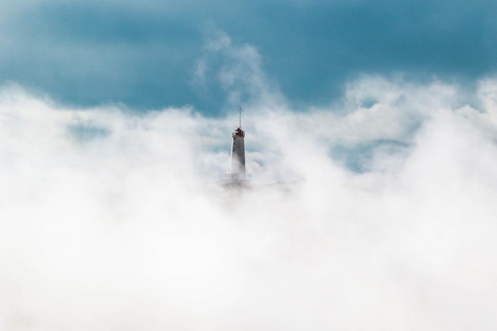 Free Image of Lighthouse emerging from misty clouds 