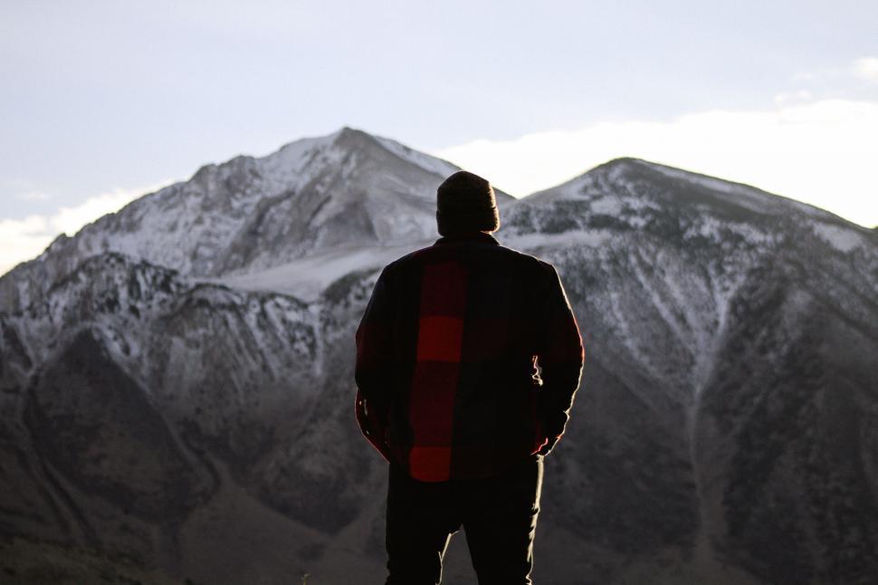Free Image of Man facing snow-covered mountain 