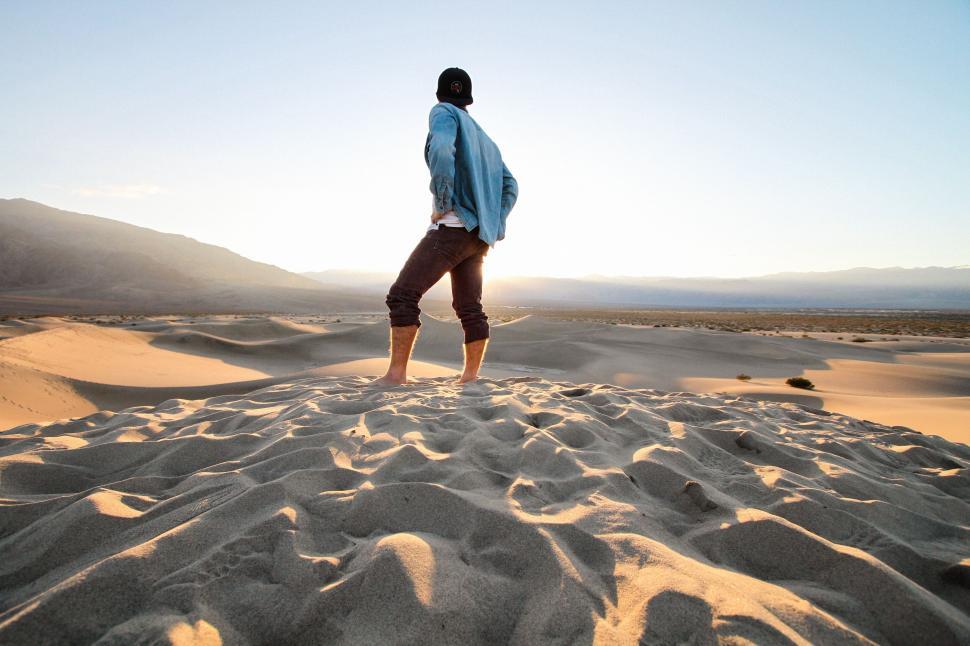 Free Image of Man standing on sand dunes at sunrise 