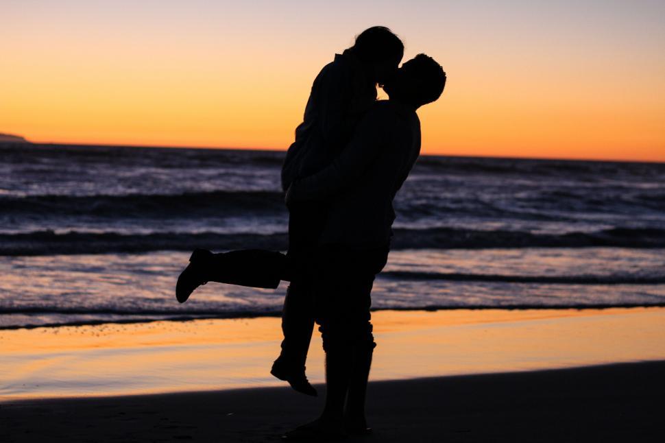 Free Image of Silhouetted couple kissing at sunset 