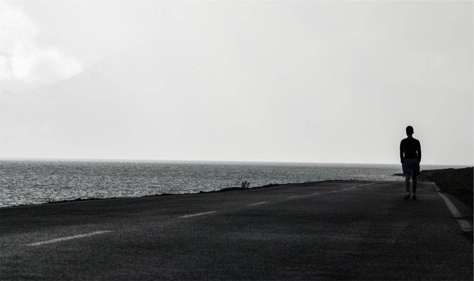 Free Image of Silhouette of a person walking on a coastal road 