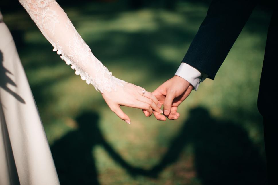 Free Image of Couple holding hands with sunlight in background 